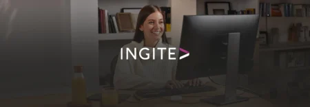 Woman working at a desktop computer in a home office with a bookshelf behind her